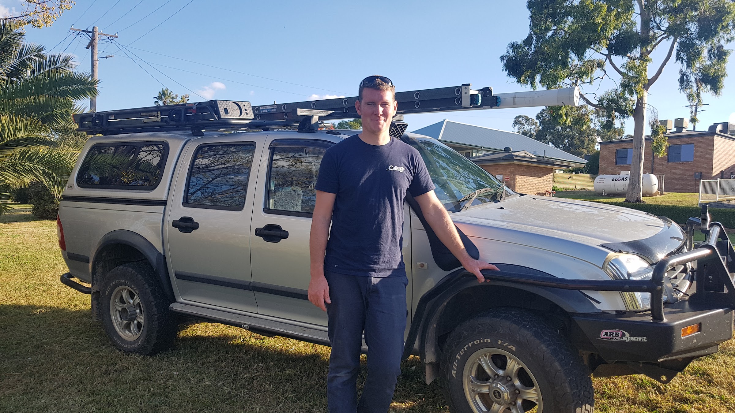 Vaughan Cusack standing beside his work ute with ladders on the roof rack